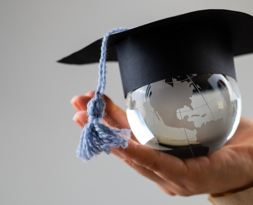 Woman holding a crystal globe wearing a graduation cap.