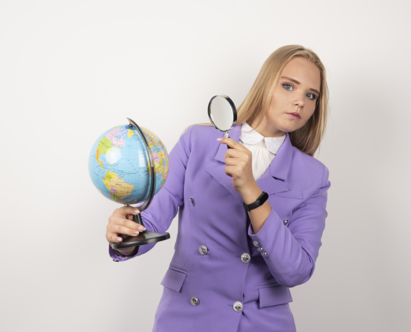 Female teacher looking at globe with magnifying glass